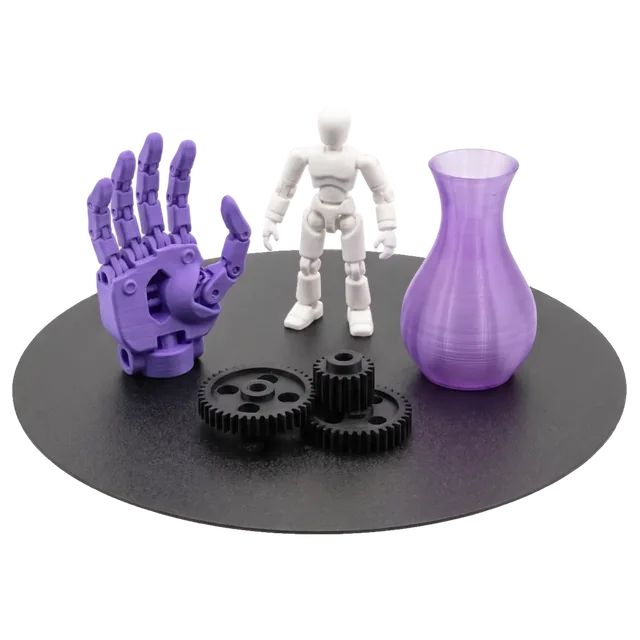 Piese printate 3D pe placa imprimantei: o mână robotică violet, o figurină, roți dințate și o vază